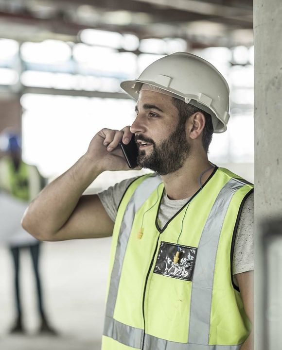 Bauleiter auf der Baustelle am Telefon